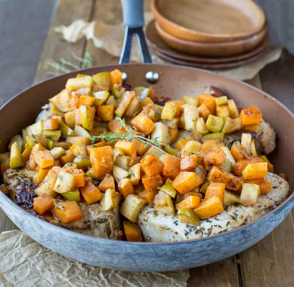Pork Chops topped with Cinnamon Apples and Butternut Squash and fresh thyme in a copper skillet