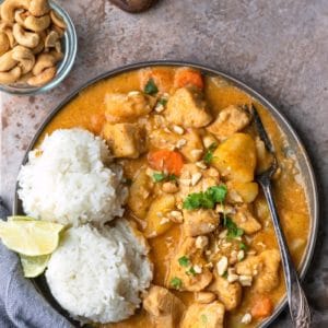 Chicken massaman curry on a plate with 2 scoops of rice