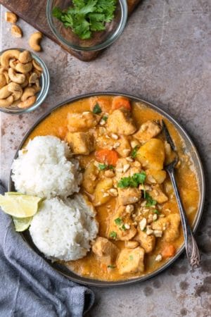 Chicken massaman curry on a plate with 2 scoops of rice