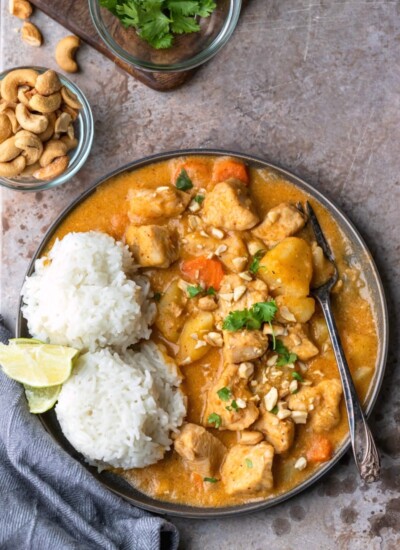 Chicken massaman curry on a plate with 2 scoops of rice