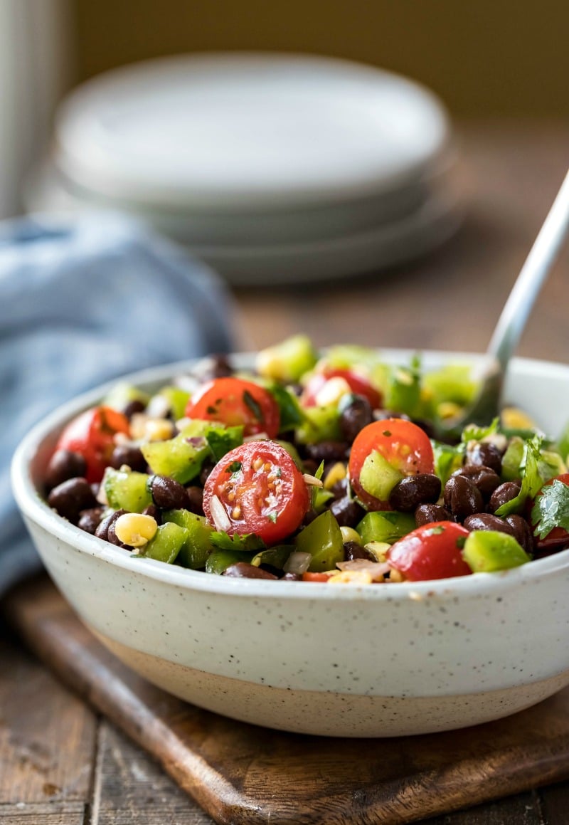 Bowl of black bean salad with a silver spoon in it
