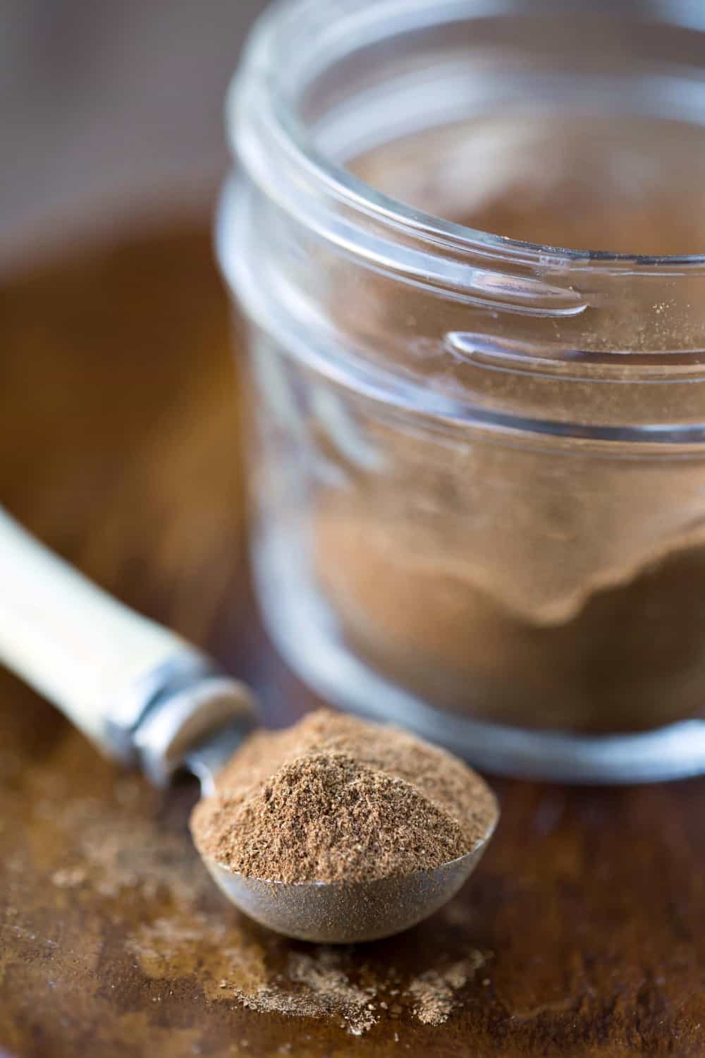 Pumpkin Pie Spice on a measuring spoon next to a glass jar 