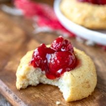 Cherry cheesecake thumbprint cookie on a wooden cutting board