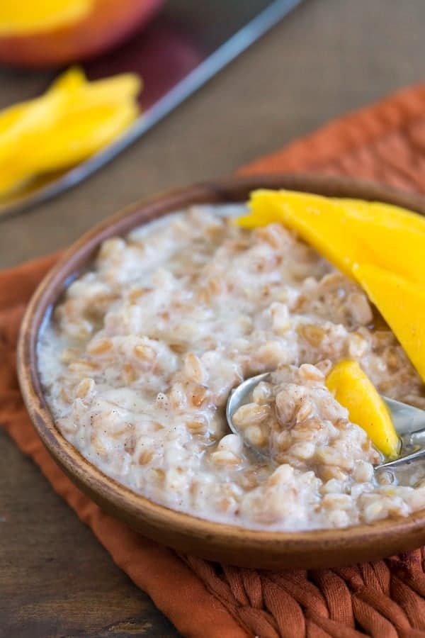 Coconut Mango Breakfast Farro next to a sliced mango.