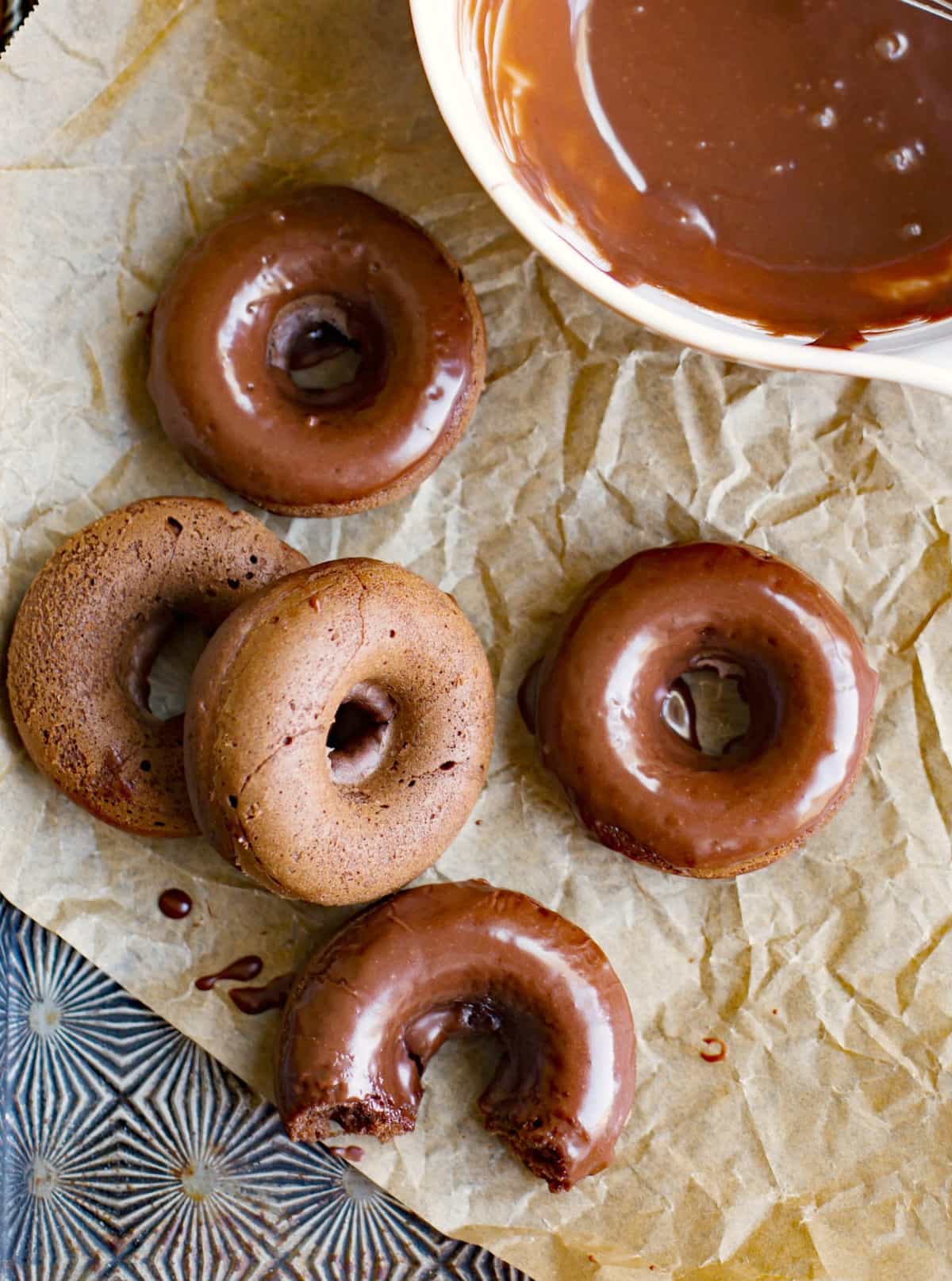 Chocolate Buttermilk Baked Donuts on a piece of brown parchment paper in a vintage baking pan.