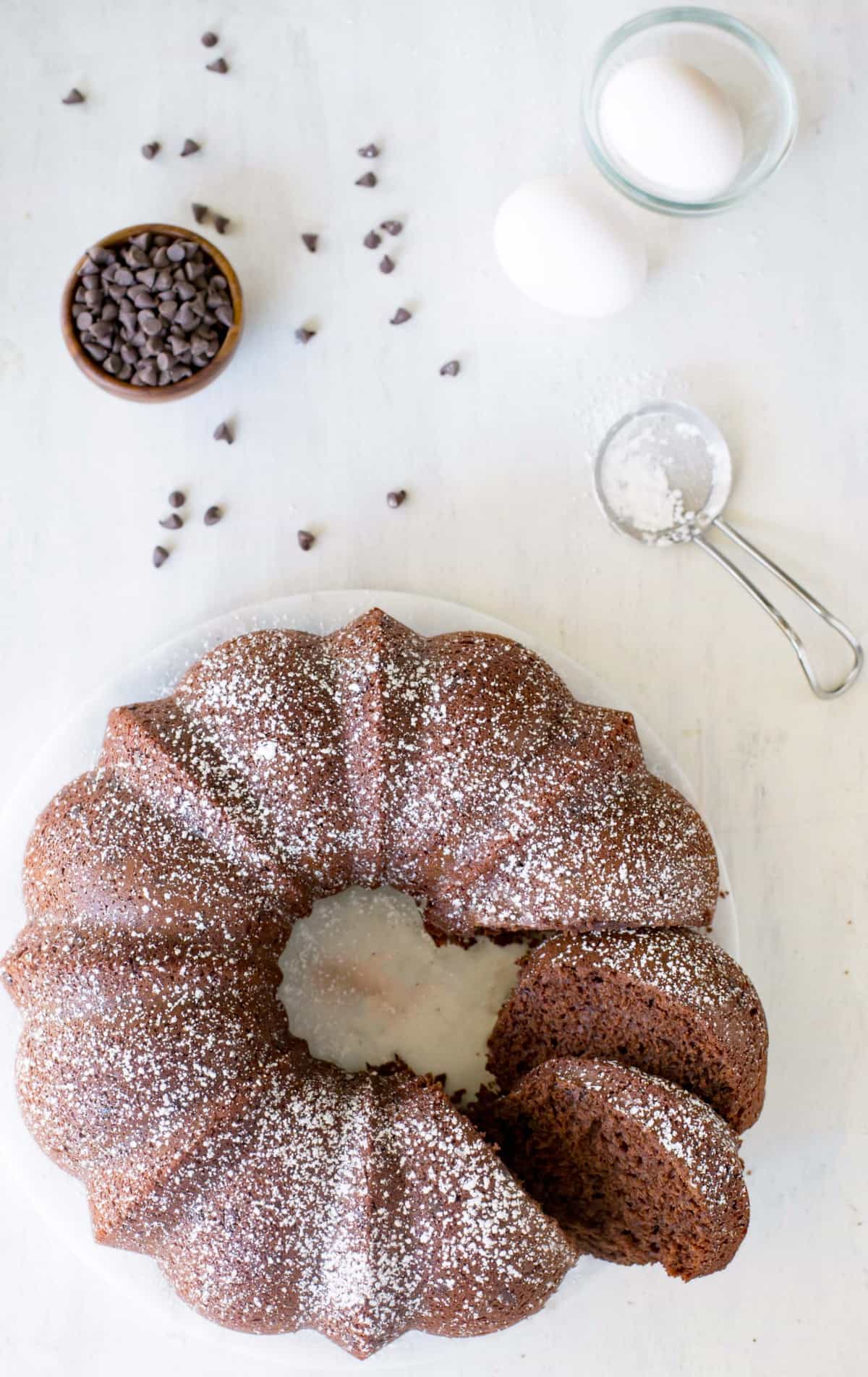 Chocolate bundt cake dusted with powdered sugar on a white plate 