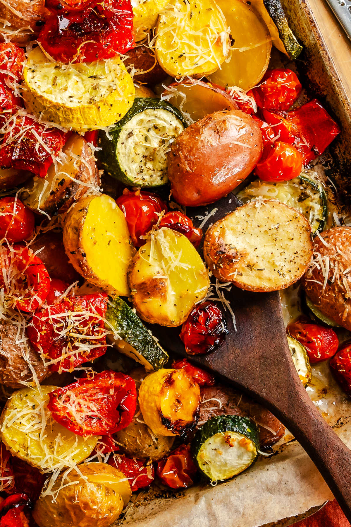 Close up photo of a wooden spoon holding roasted summer vegtables.