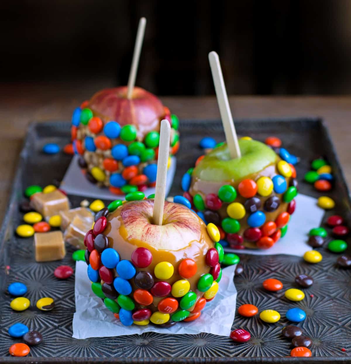 Three M&M Caramel Apples on a vintage baking sheet. 