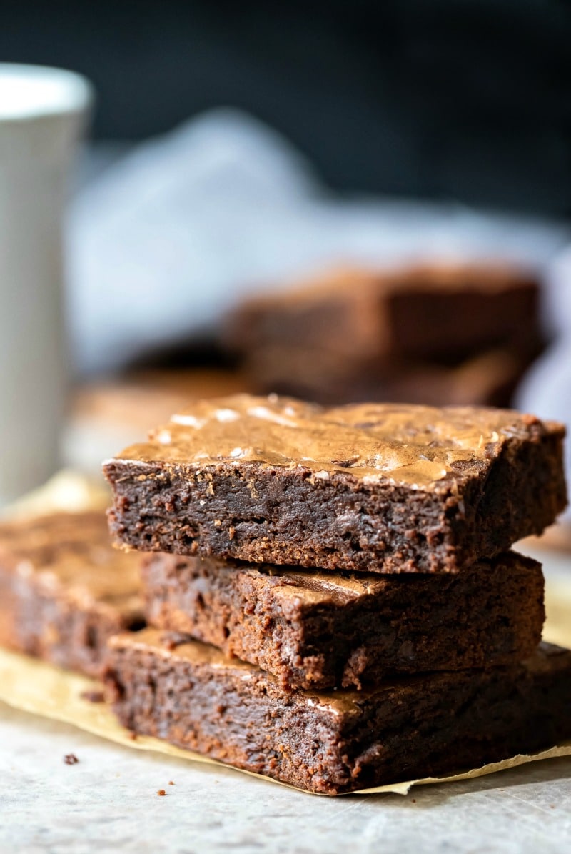 Stack of three brownies on a piece of brown parchment paper