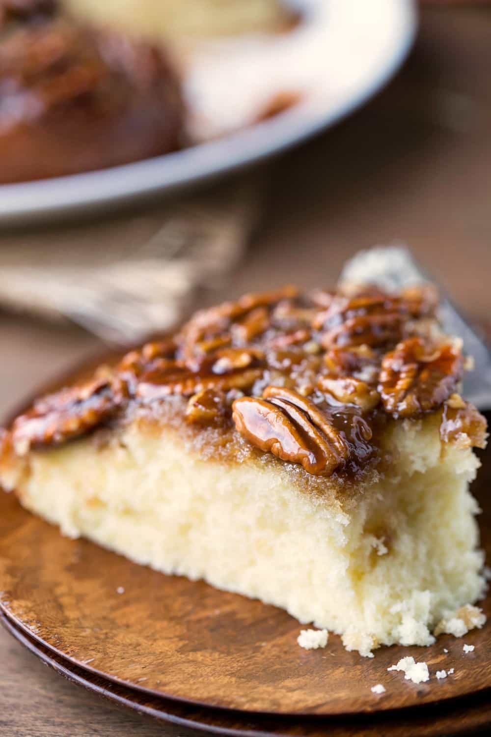 Slice of Pecan Pie Upside-Down Cake on a wooden plate with a bite missing