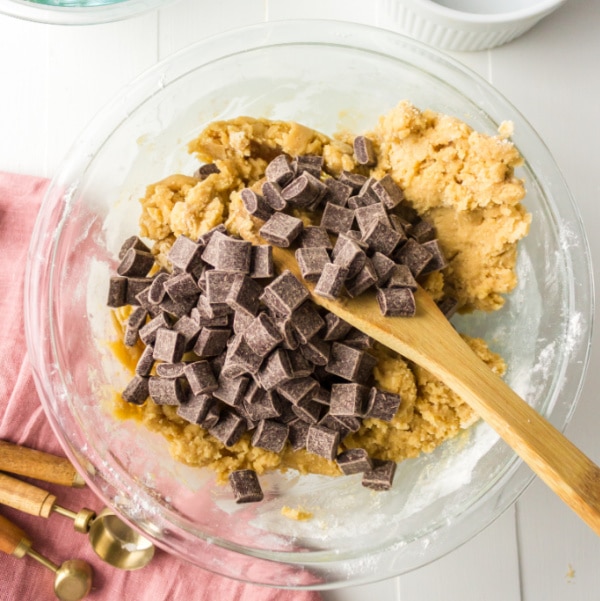 chocolate chunks on cookie dough in a glass mixing bowl