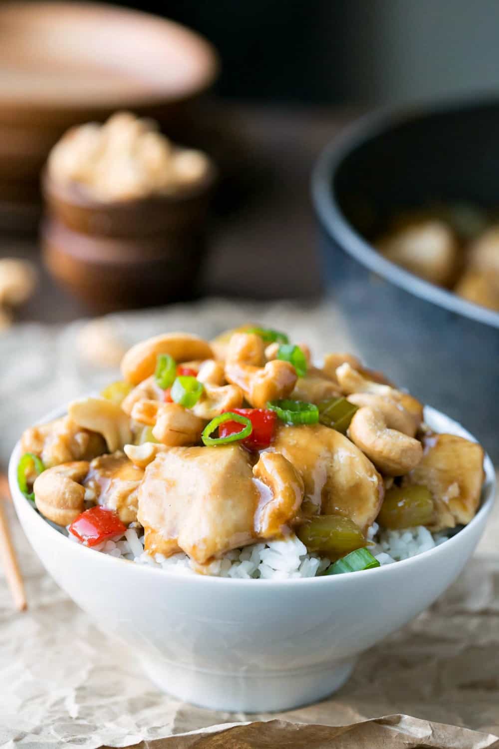 Dish of cashew chicken next to a black skillet