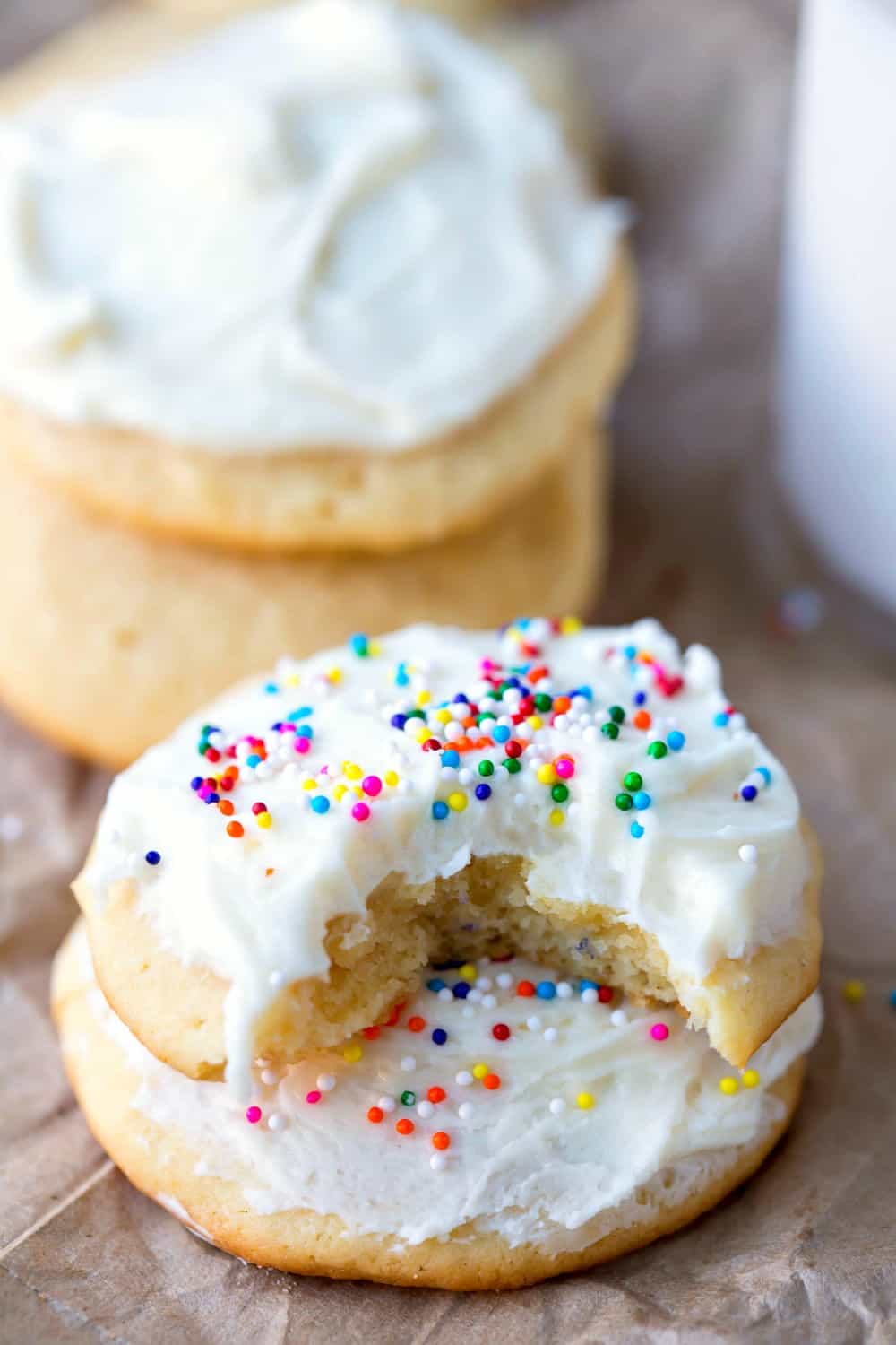 Sour Cream Sugar Cookies with a bite missing next to a stack of cookies
