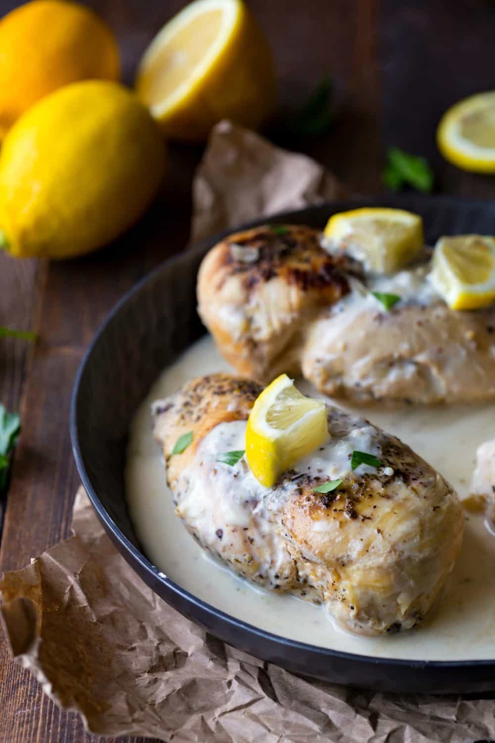 Creamy Crock Pot Chicken topped with fresh lemon slices in a metal dish