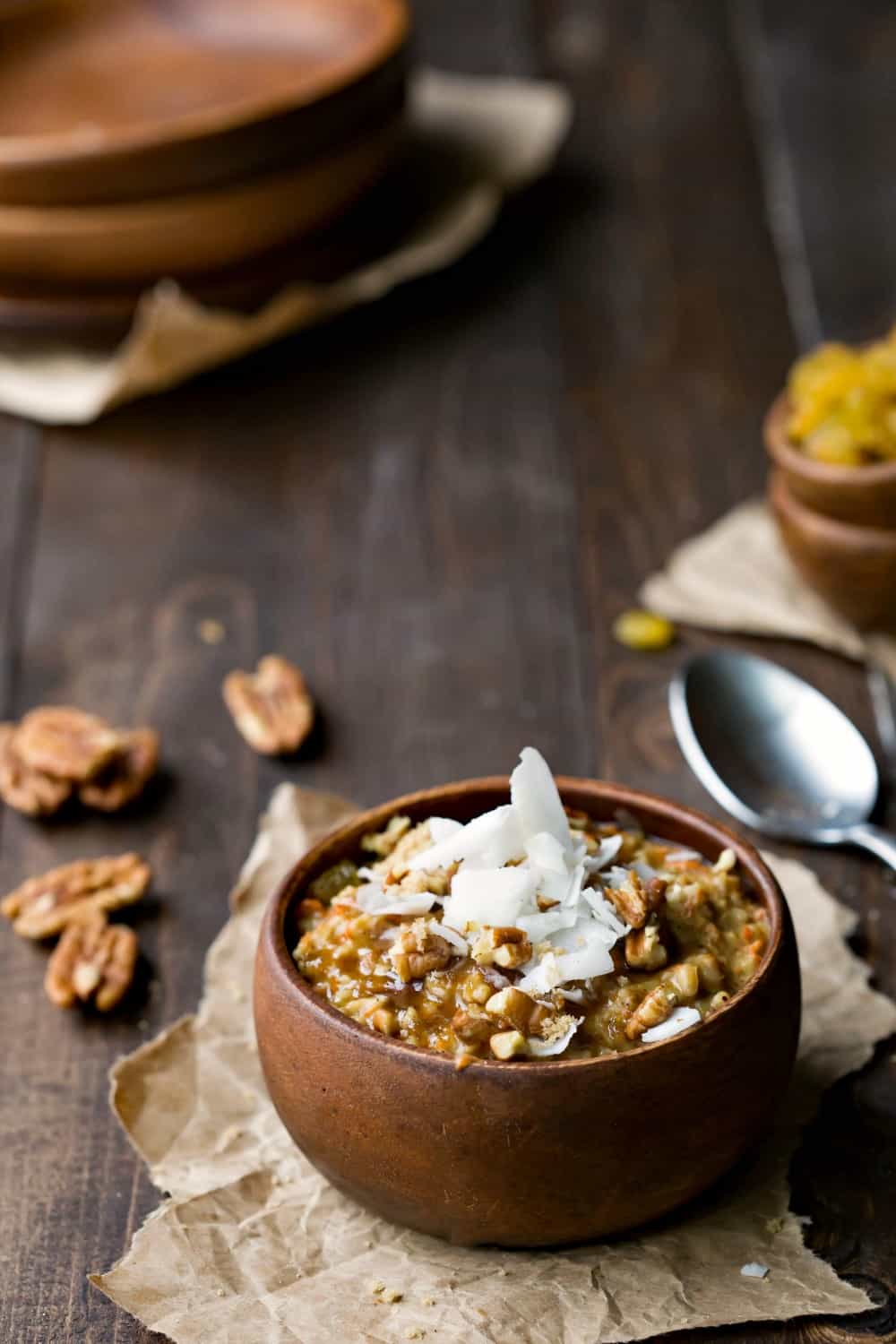 Crock Pot Carrot Cake Oatmeal topped with coconut and chopped pecans in a wooden bowl