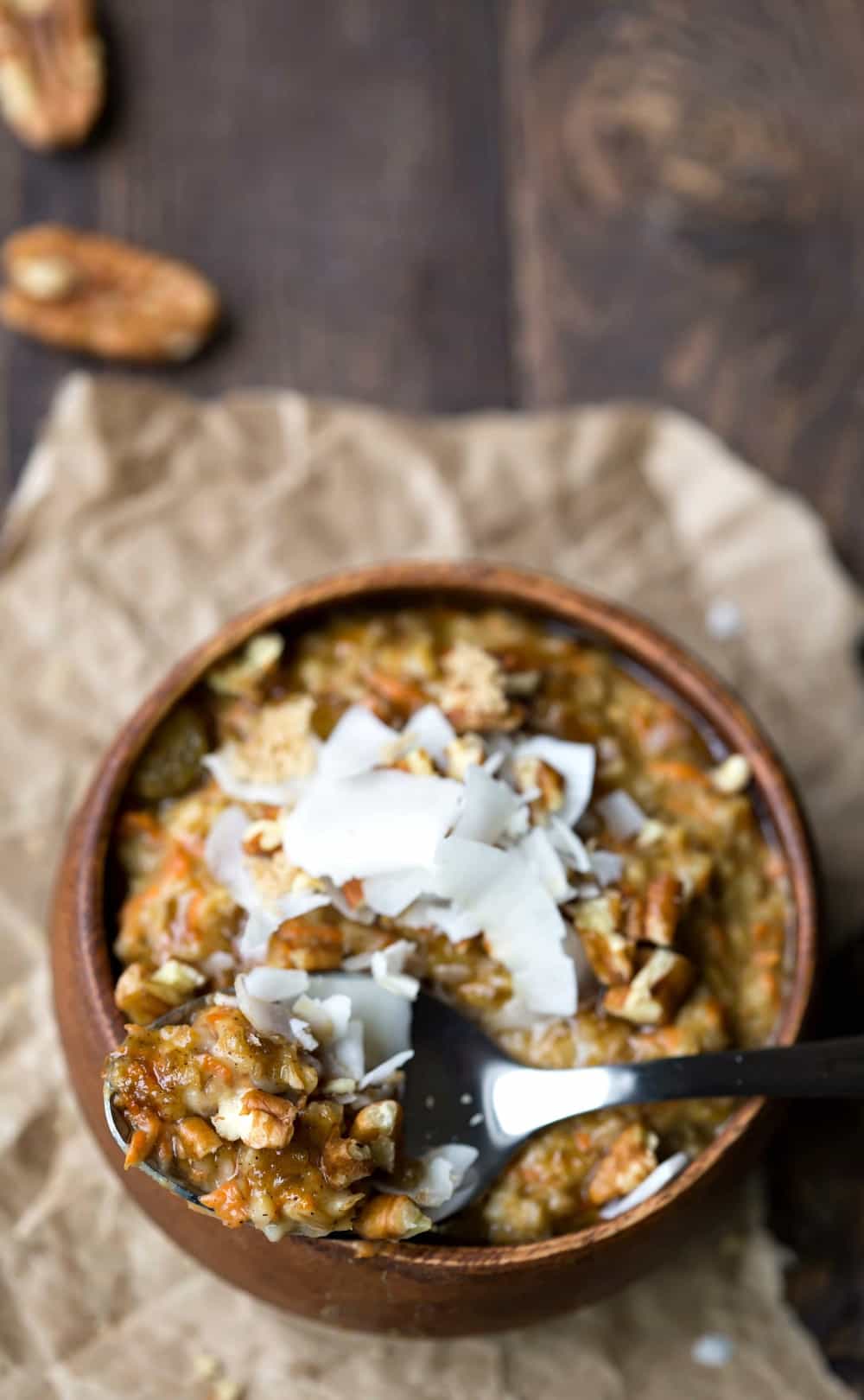 Crock Pot Carrot Cake Oatmeal with a spoonful of oatmeal sitting on the edge of a wooden bowl