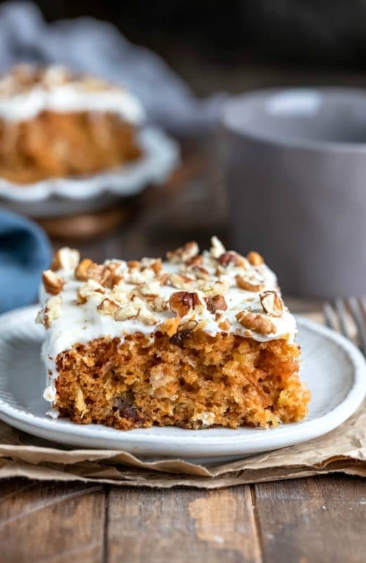 Slice of carrot cake topped with cream cheese frosting and pecans