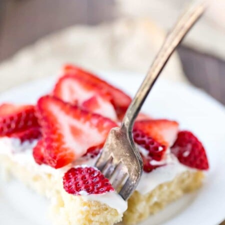 Strawberry Shortcake Bars on a white plate with a fork taking a bite.
