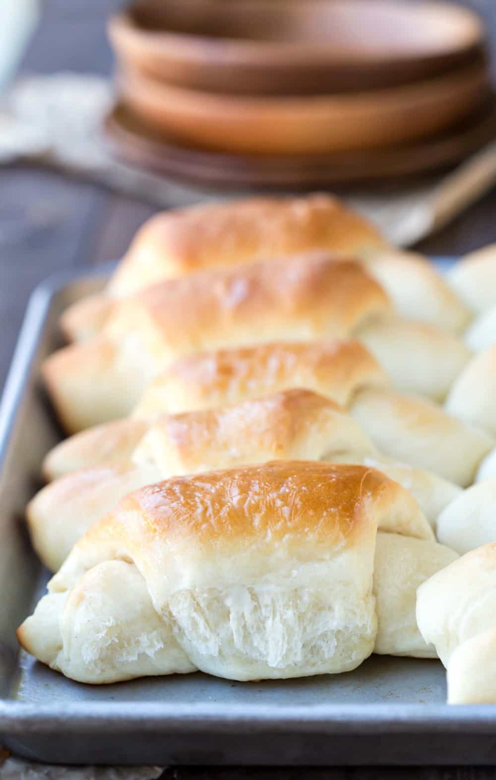 Butterhorn Dinner Rolls next to a stack of wooden plates