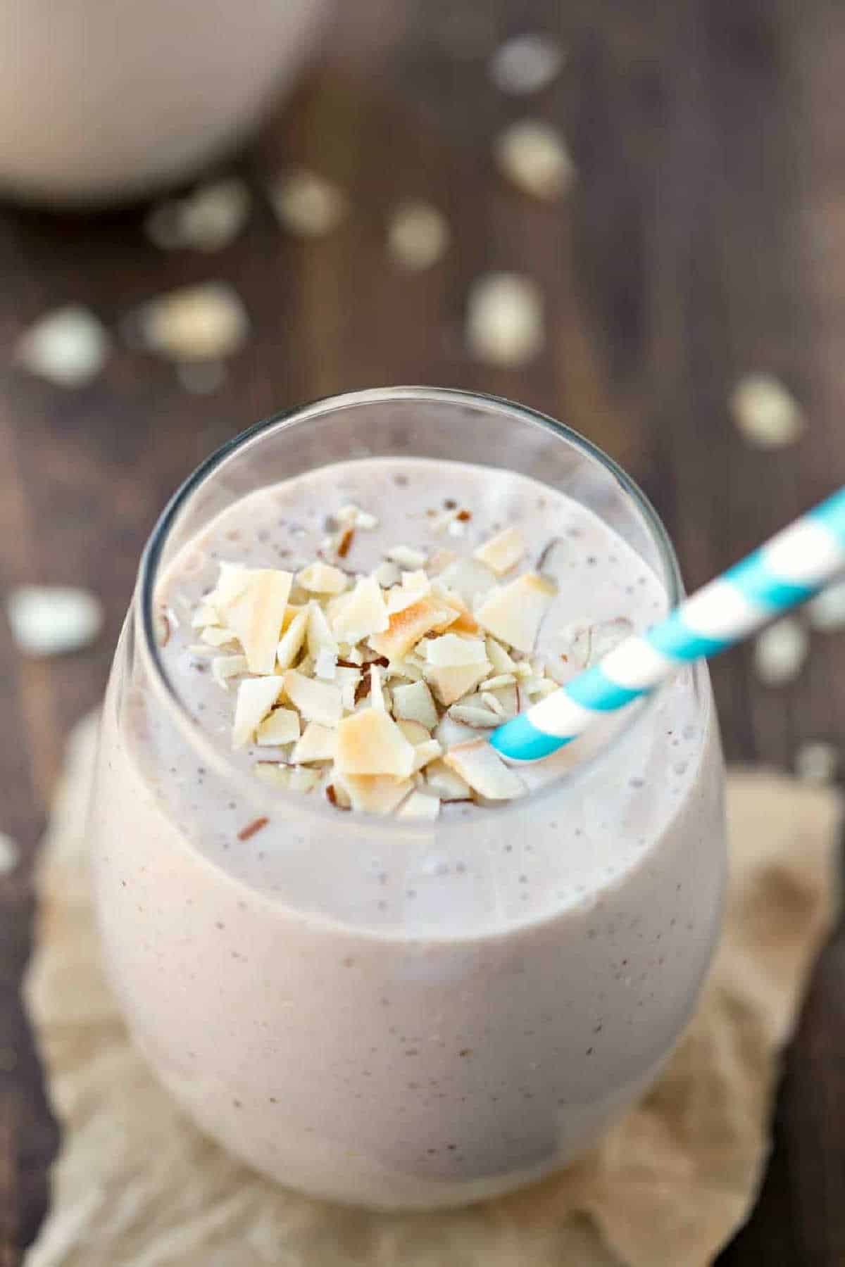 Chocolate Almond Coconut Banana Smoothie in a glass with a blue striped straw.