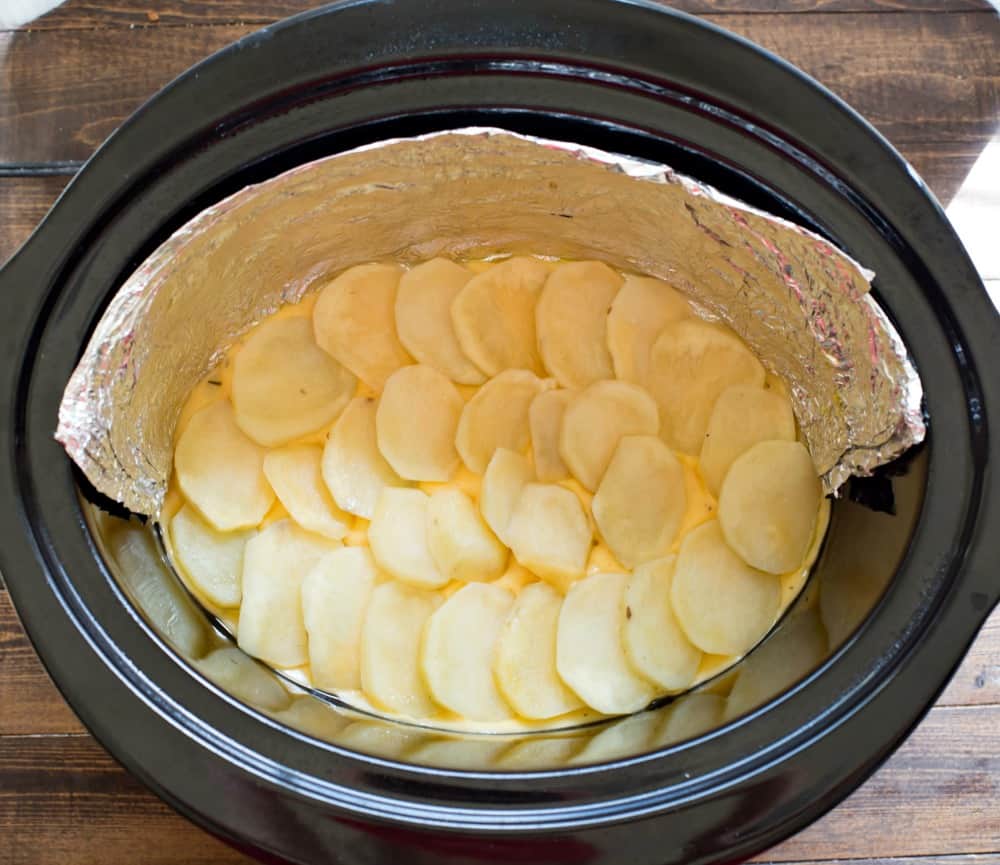 Slow Cooker Scalloped Potatoes with Ham Slices of potato in a slow cooker insert