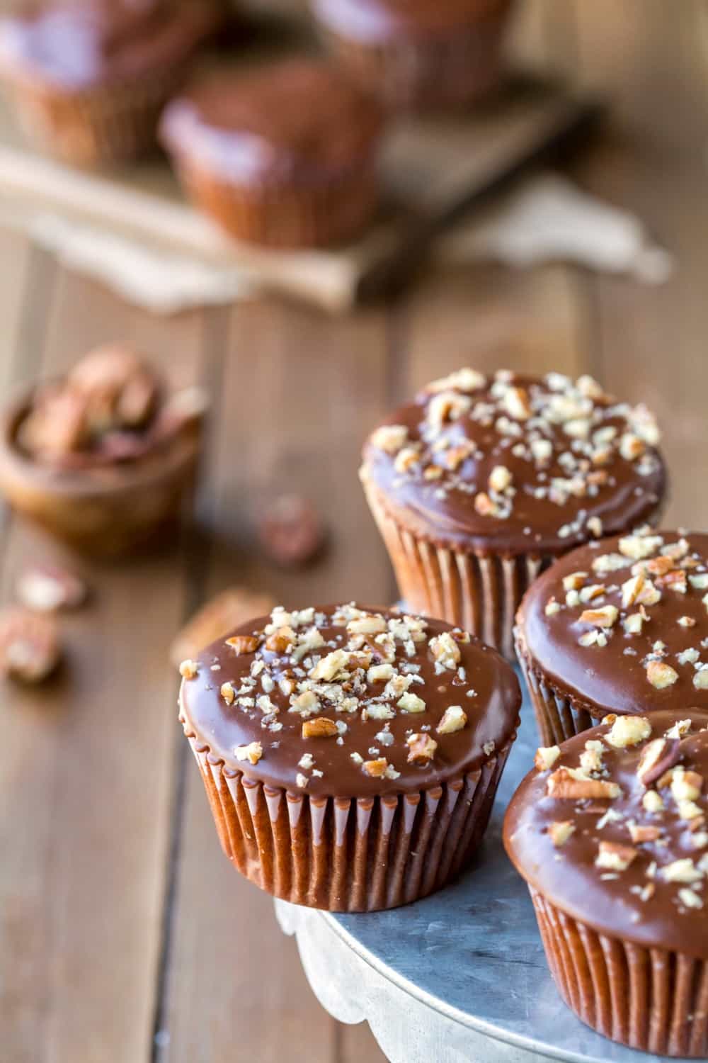 Texas Sheet Cake Cupcakes topped with chopped pecans on a metal cake stand