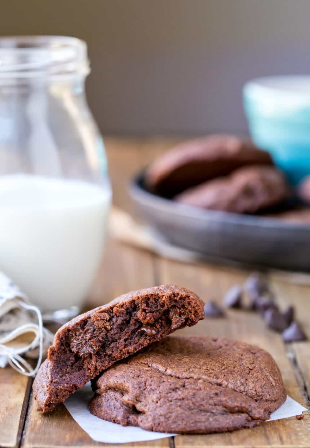 Bakery Style Double Chocolate Chip Cookies on a piece of parchment paper next to a glass of milk