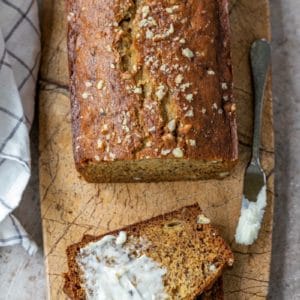 Half buttered slice of banana bread on a marble cutting board