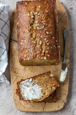 Half buttered slice of banana bread on a marble cutting board