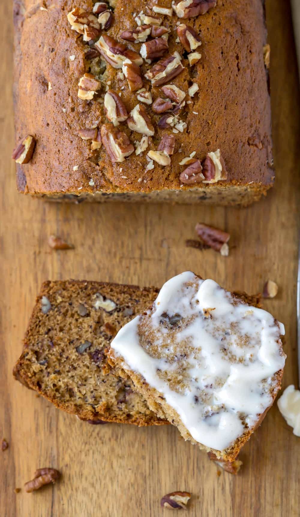 Banana Nut Bread Half a slice of buttered Banana Nut Bread on a wooden cutting board