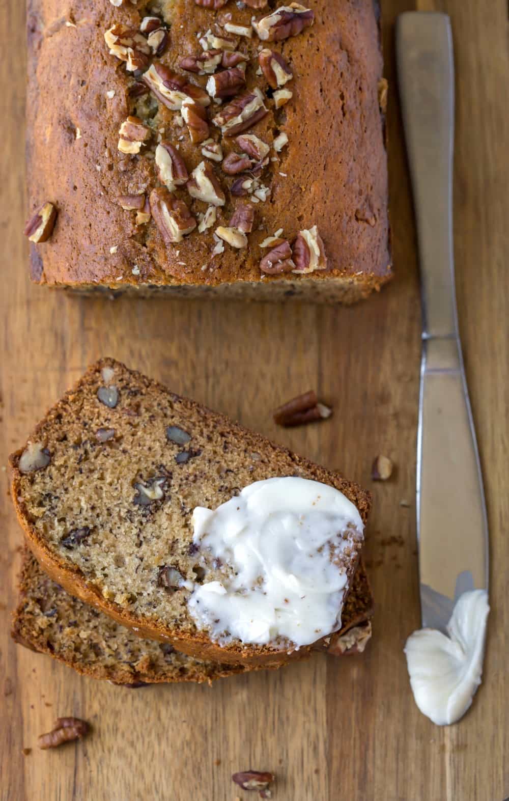 Slice of Banana Nut Bread next to knife with butter on it