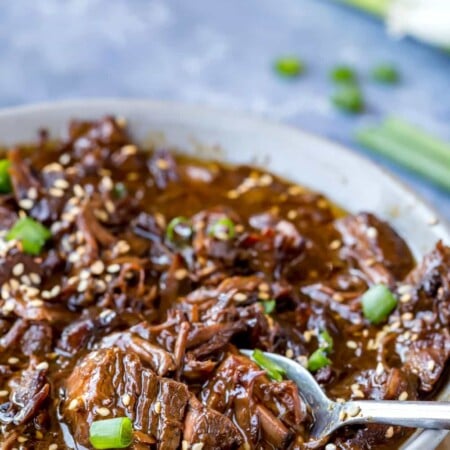 Slow Cooker Korean Beef with a spoon scooping up beef.