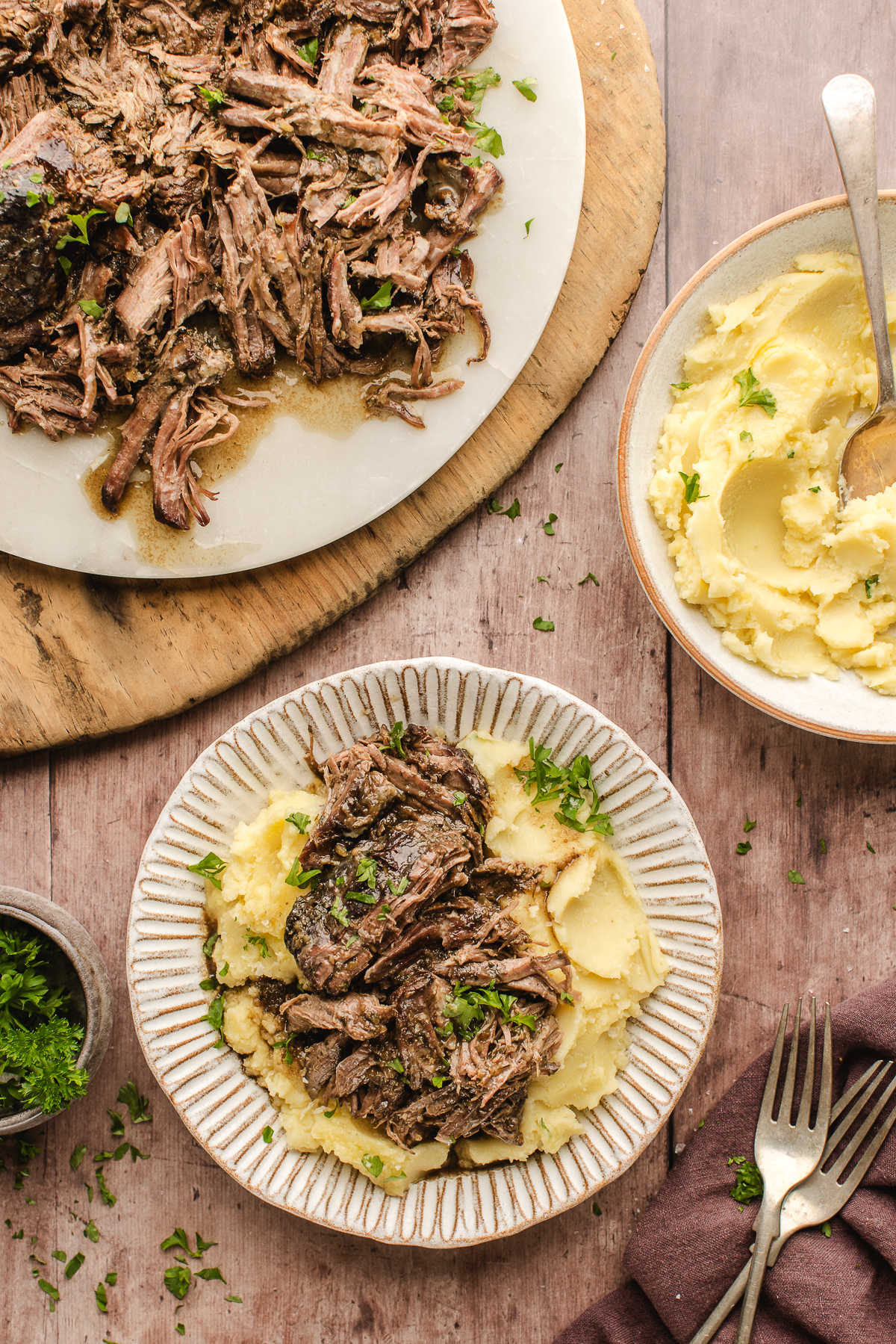 A plate of Mississippi pot roast next to dishes of meat and mashed potatoes.