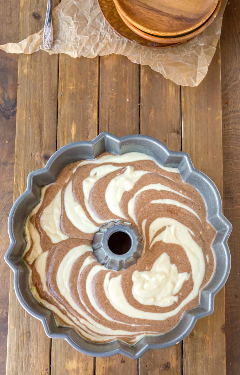 cinnamon swirl bundt cake batter in a bundt pan on a wooden background