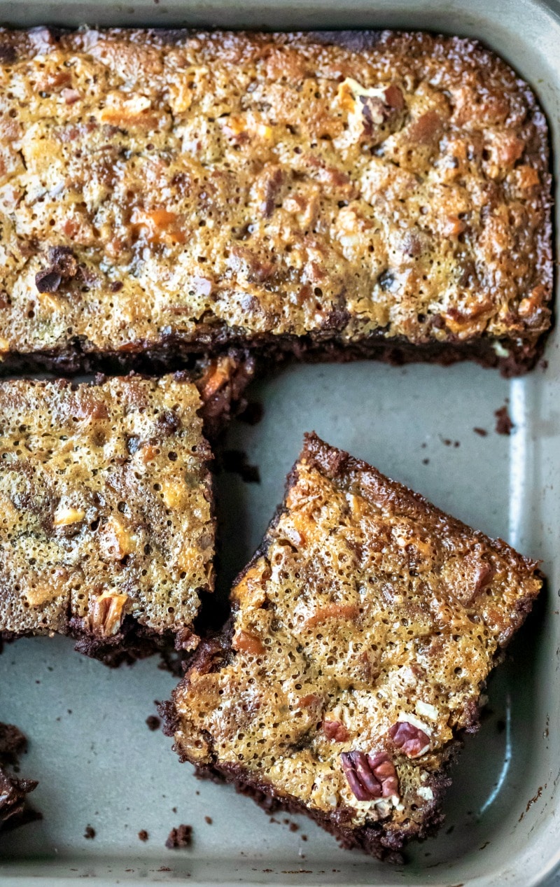 Pan of pecan pie brownies with a piece cut 