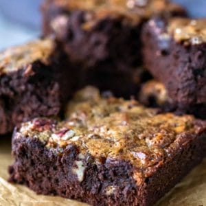 A stack of pecan pie brownies on a piece of brown parchment paper.