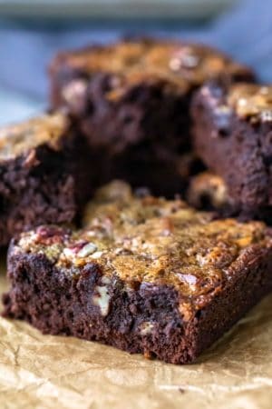 A stack of pecan pie brownies on a piece of brown parchment paper.