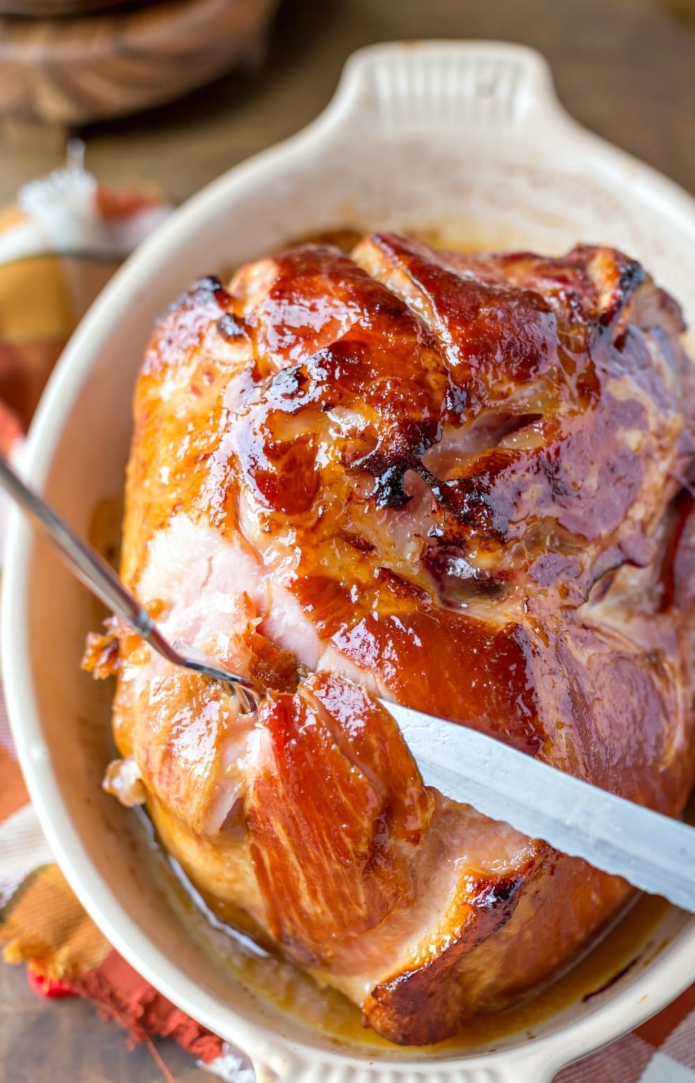 Knife and form slicing Maple Glazed Ham in a baking dish