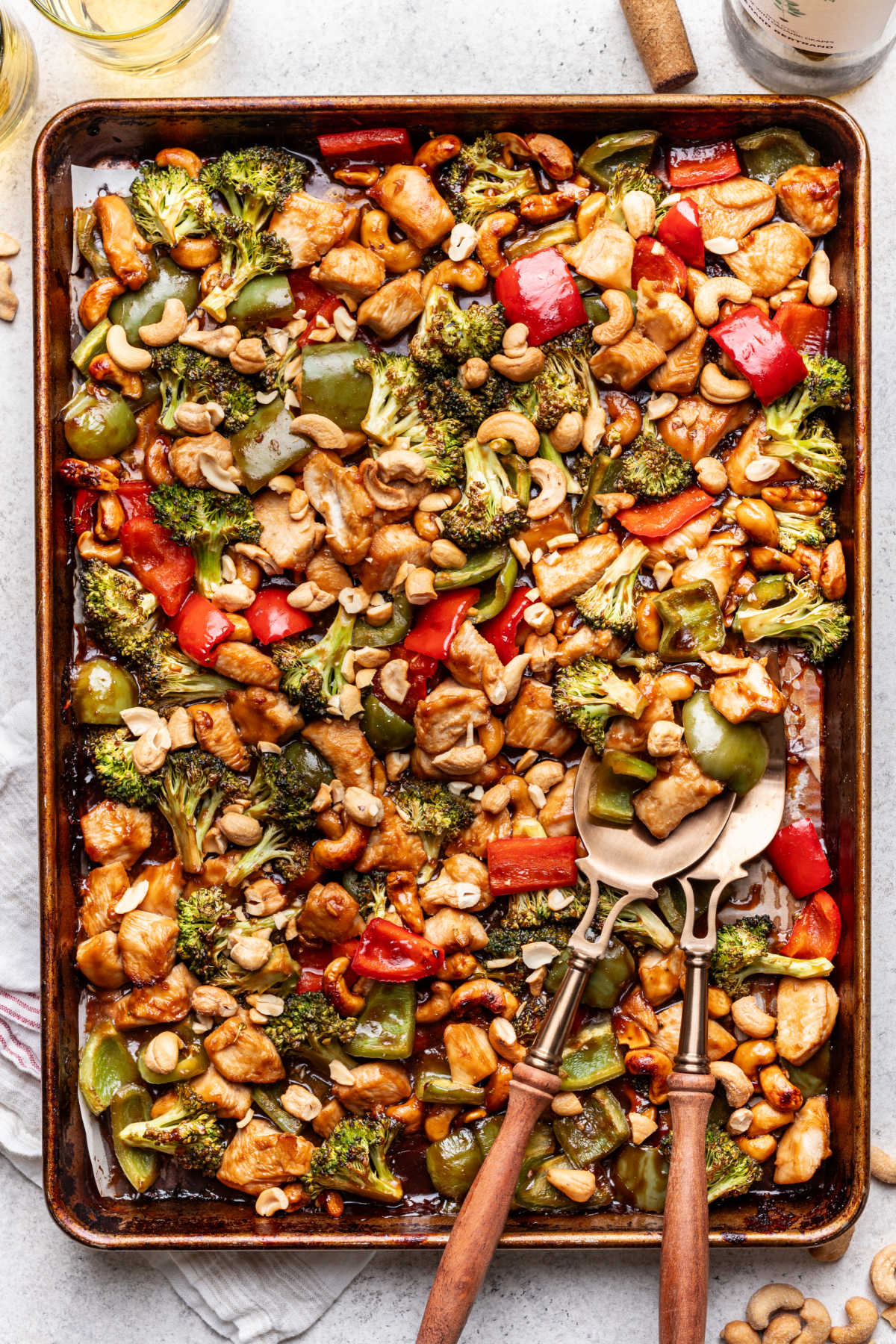 Sheet pan cashew chicken with two wooden handled forks in it.