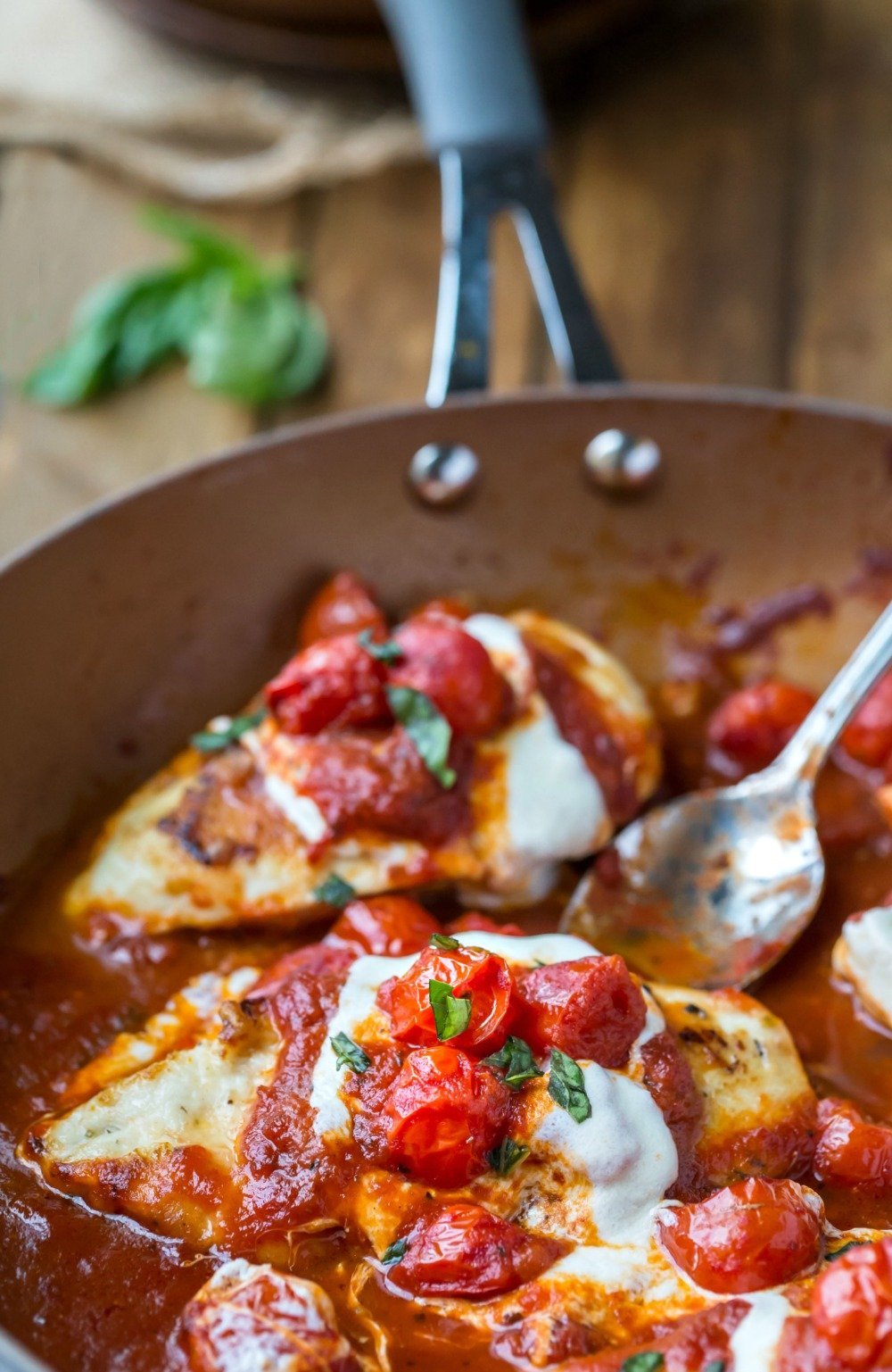 Skillet chicken parmesan in the pan with a spoon
