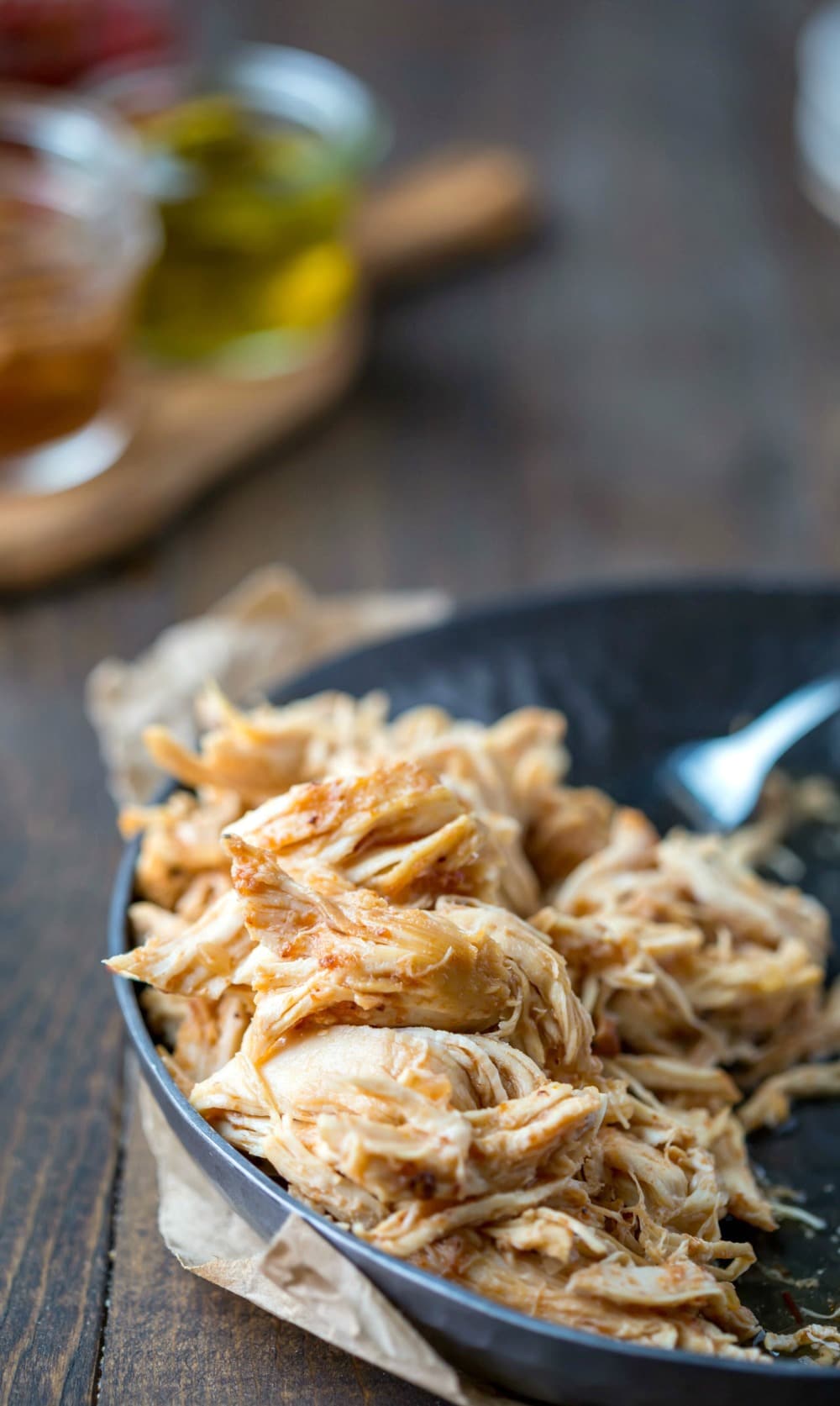 Shredded slow cooker honey chipotle chicken in a metal dish 