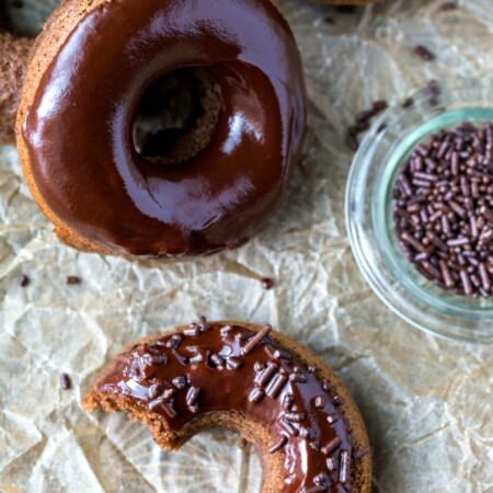 Half of a chocolate baked donut topped with chocolate glaze and chocolate sprinkles.