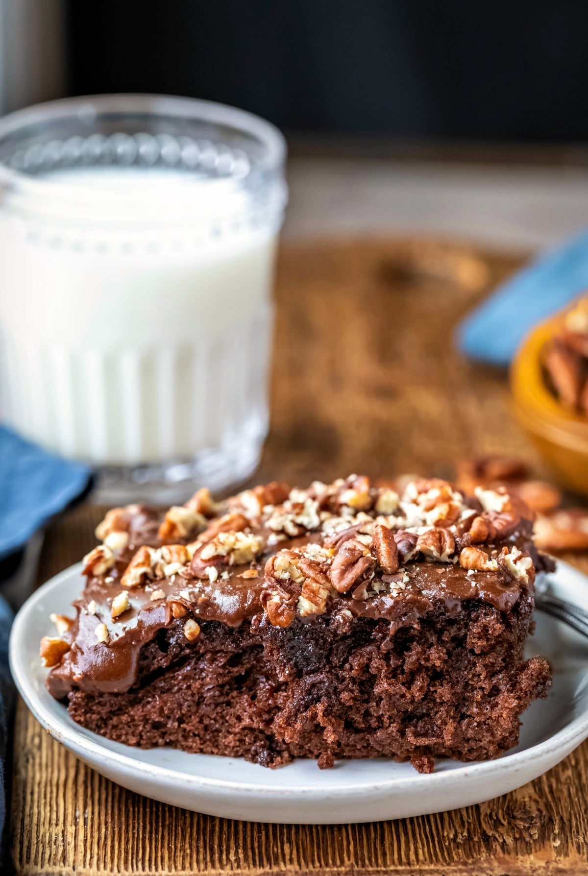 Slice of coca cola cake next to a glass of milk.