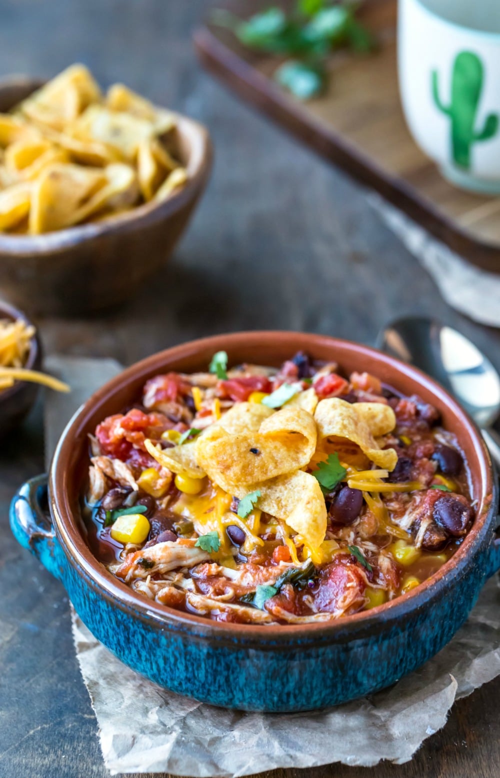 Slow Cooker Chicken Frito Chili in a blue dish next to a gold spoon