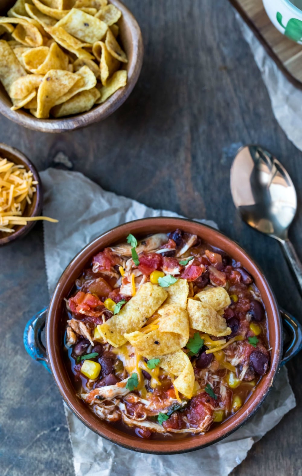 Slow Cooker Chicken Frito Chili in a blue bowl next to a bowl of fritos