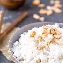 Coconut rice in a blue bowl topped with cashew pieces