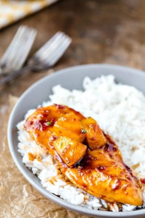 Pineapple chicken on a bed of rice in a gray bowl.