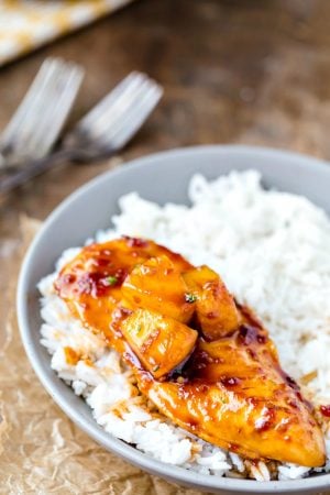 Pineapple chicken on a bed of rice in a gray bowl.