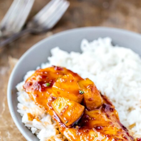Pineapple chicken on a bed of rice in a gray bowl.