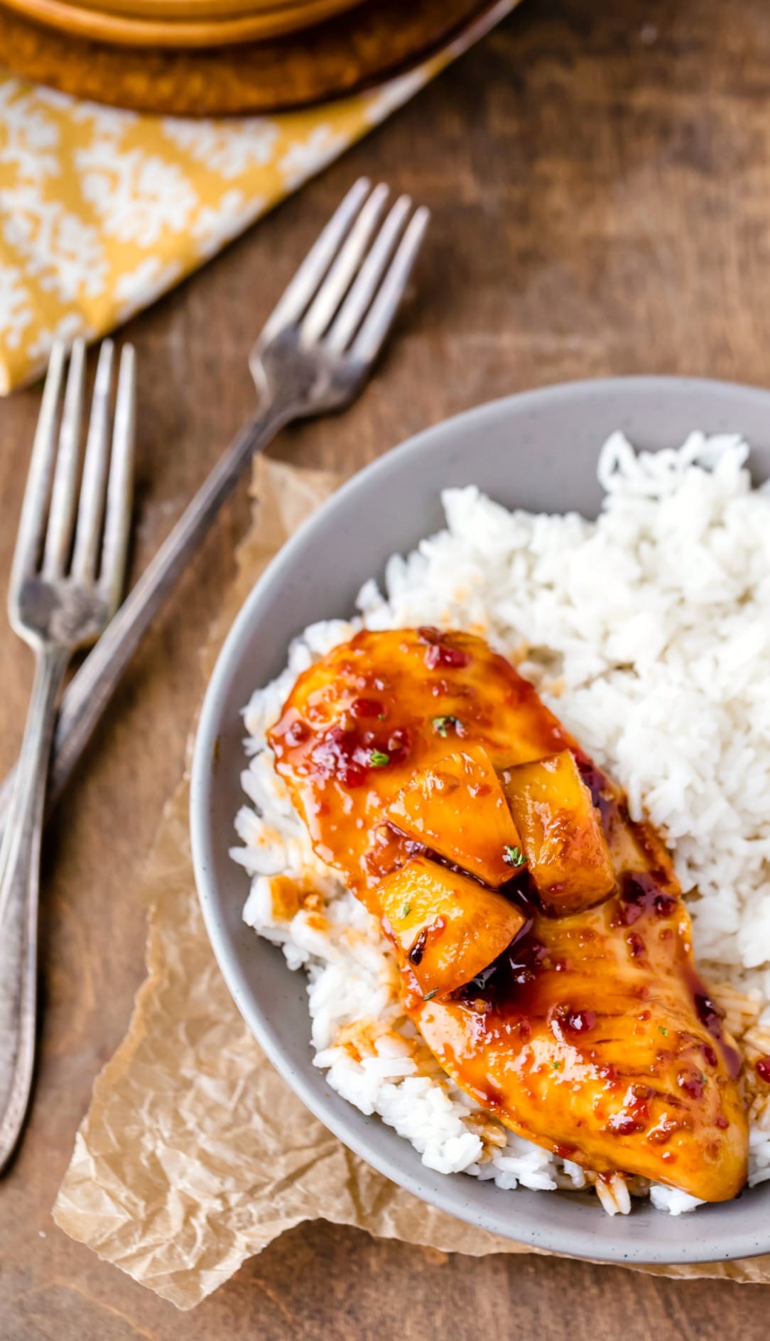 Pineapple chicken with coconut rice in a blue dish next to two forks